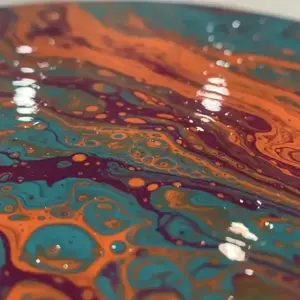 A vibrant macro photograph of fluid art featuring swirling teal, orange, and deep purple acrylic paint with a glossy, reflective surface and intricate cell-like patterns.